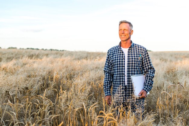 Hombre sonriente de pie en un campo de trigo