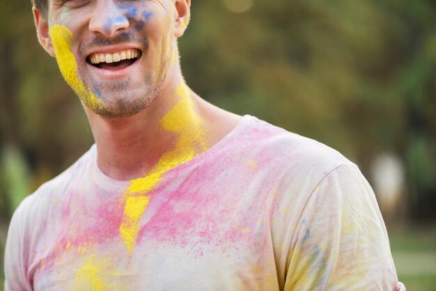 Hombre sonriente con pintura coloreada en holi