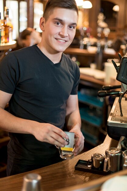 Hombre sonriente poniendo ba de té en la taza