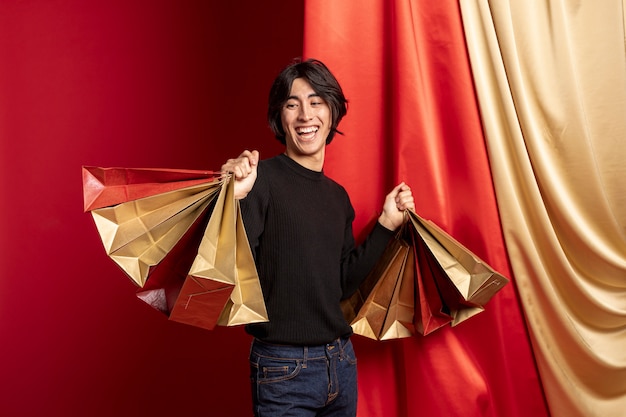 Foto gratuita hombre sonriente posando con bolsas de compras para el año nuevo chino