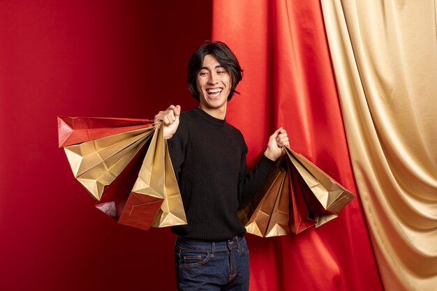 Hombre sonriente posando con bolsas de compras para el año nuevo chino