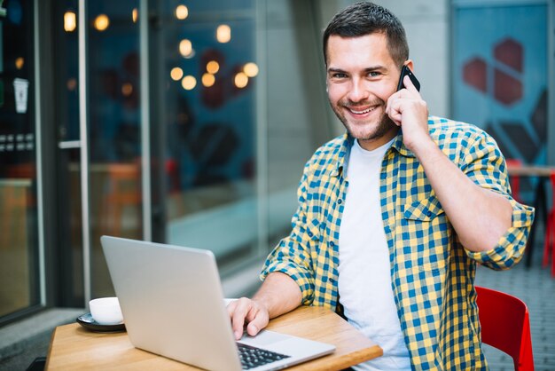 Hombre sonriente posando con gadgets en café