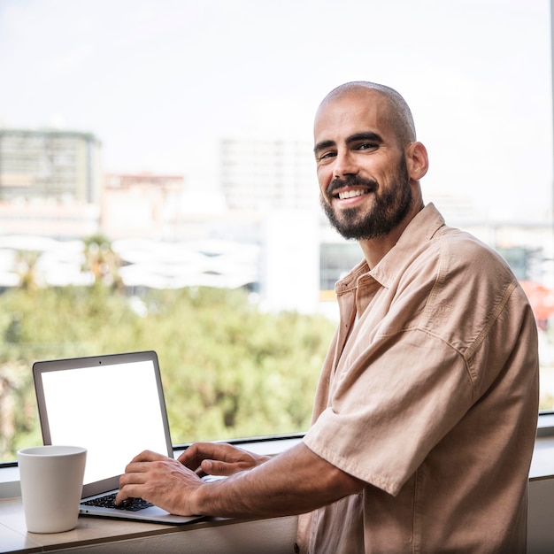 Foto gratuita hombre sonriente posando junto a la ventana