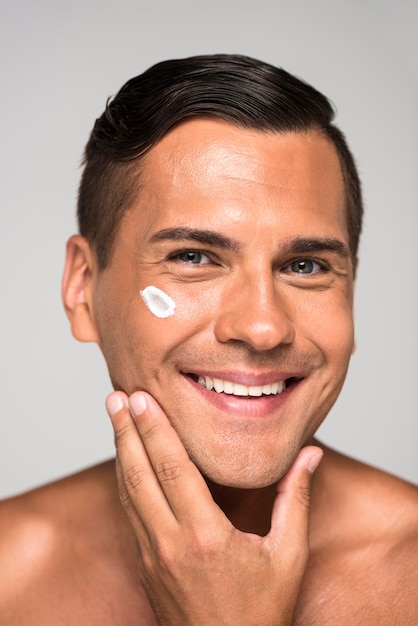 Hombre sonriente de primer plano con crema facial