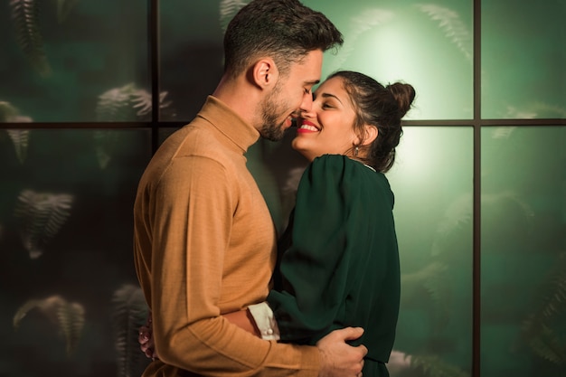 Foto gratuita hombre sonriente que besa a la mujer feliz cerca de la pared