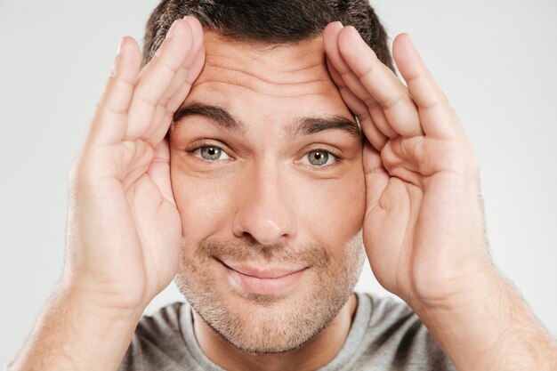 Hombre sonriente que cubre la cara con las manos.