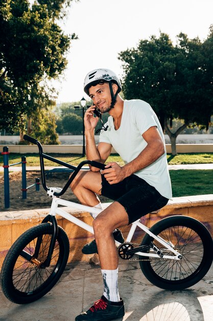 Hombre sonriente que habla en el tiro largo del teléfono