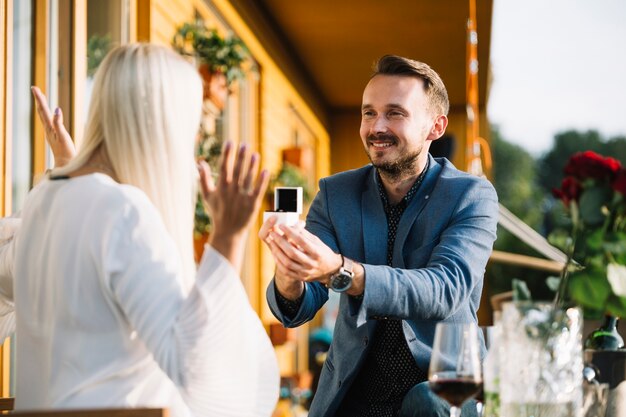 Hombre sonriente que muestra un anillo de compromiso a su novia