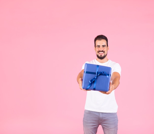 Hombre sonriente que ofrece la situación presente contra fondo rosado