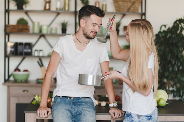 Foto gratuita hombre sonriente que prueba la sopa preparada por la mujer en la cocina