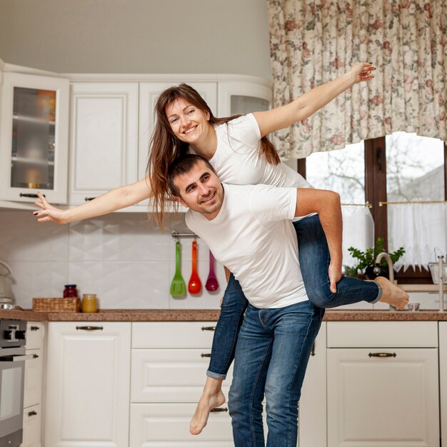 Hombre sonriente que retiene a la mujer en su parte posterior