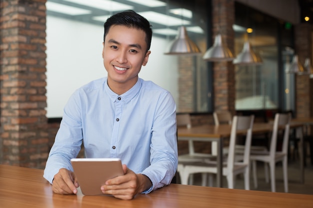 Hombre sonriente que se sienta en el vector del café con la tablilla