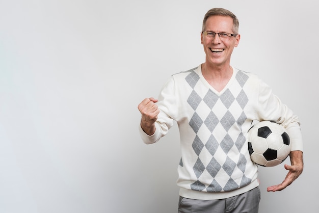 Hombre sonriente que sostiene un balón de fútbol con espacio de copia