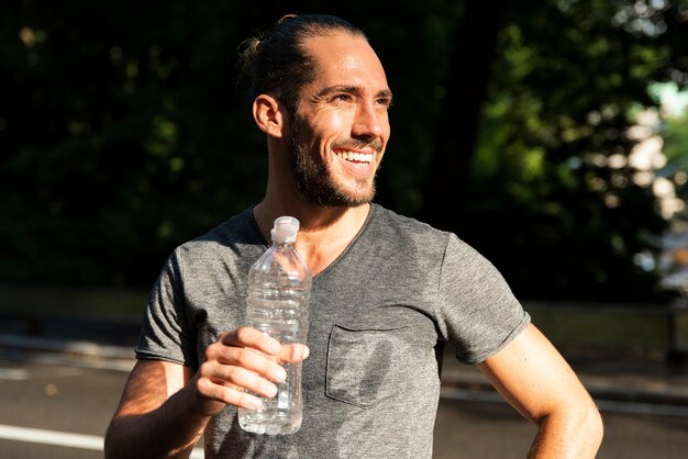 Hombre sonriente que sostiene la botella de agua