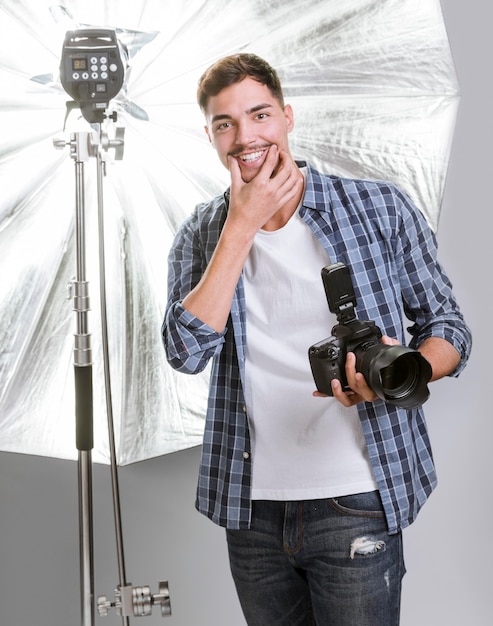 Hombre sonriente que sostiene una cámara profesional