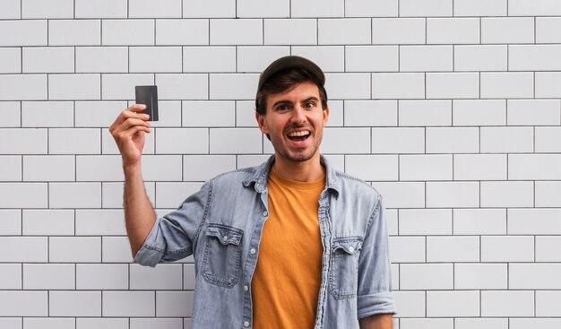 Hombre sonriente que sostiene el coche en el fondo de la pared