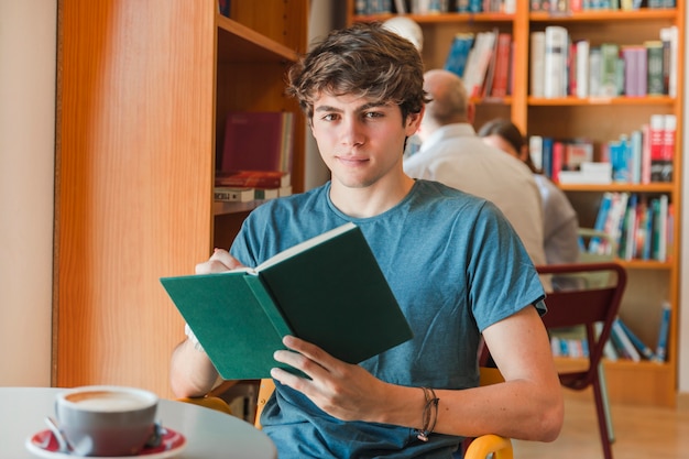 Hombre sonriente que sostiene el libro en las manos