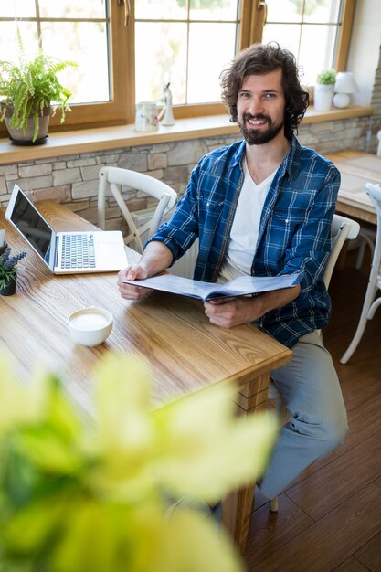 Hombre sonriente que sostiene menú en la cafetería