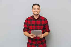 Foto gratuita hombre sonriente que sostiene la tableta y mirando a la cámara