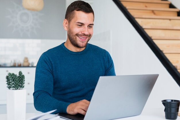 Hombre sonriente que trabaja en la computadora portátil en casa