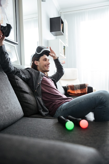 Hombre sonriente sentado en casa en casa jugar juegos