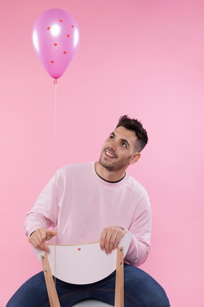 Hombre sonriente en silla cerca del globo violeta