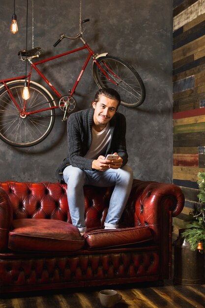 Hombre sonriente en sofá debajo de bicicleta