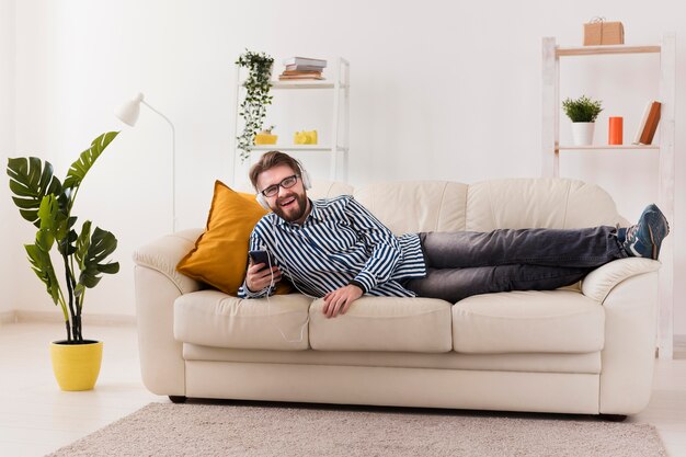 Hombre sonriente en el sofá disfrutando de la música