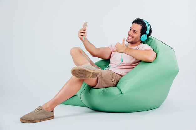 Hombre sonriente en sofá haciendo foto con smartphone