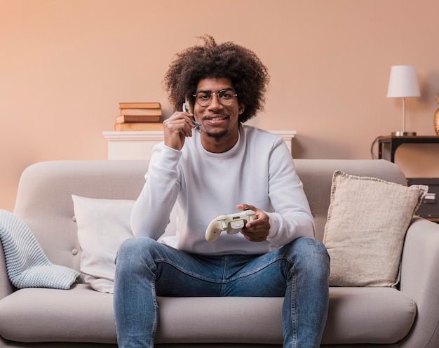 Foto gratuita hombre sonriente en el sofá jugando juegos