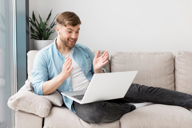 Hombre sonriente en sofá con laptop