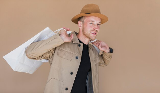 Hombre sonriente con sombrero marrón y bolsas de compras