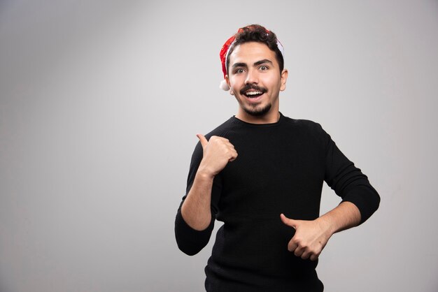 Hombre sonriente con sombrero de Santa mostrando los pulgares para arriba.