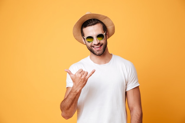 Hombre sonriente en sombrero de verano mirando cámara aislada gesticular