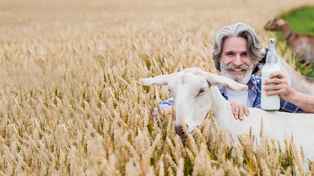 Hombre sonriente sosteniendo una botella de leche de cabra