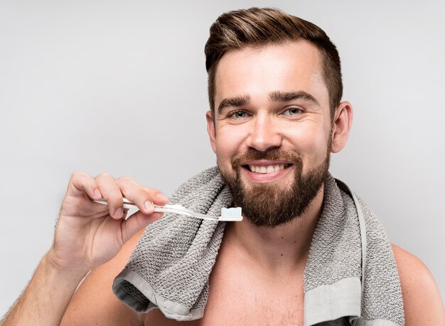 Hombre sonriente sosteniendo un cepillo de dientes