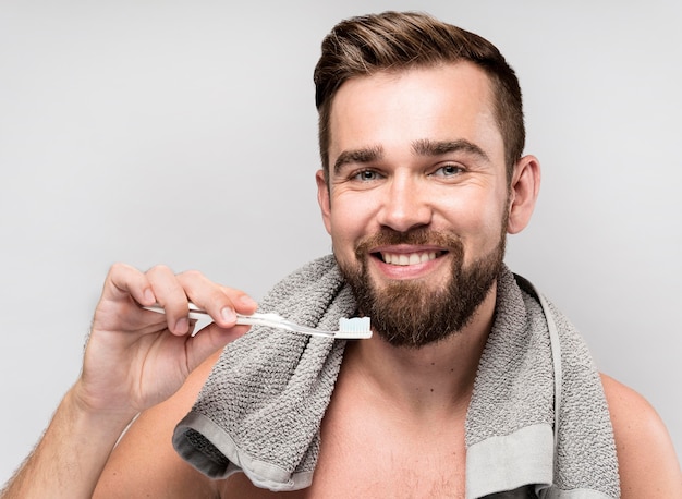 Hombre sonriente sosteniendo un cepillo de dientes