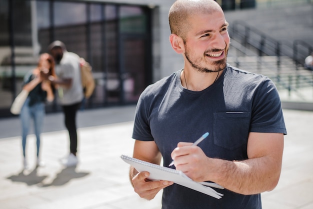 Hombre sonriente sosteniendo la escritura del cuaderno