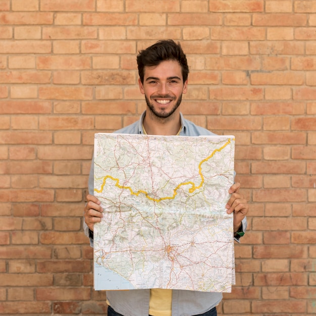 Foto gratuita hombre sonriente sosteniendo un mapa abierto