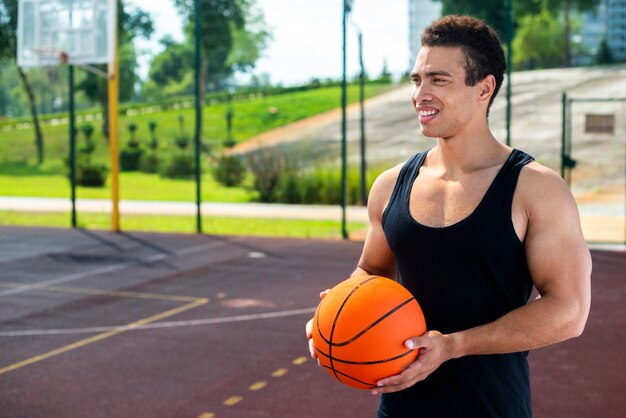 Hombre sonriente sosteniendo una pelota en la cancha de baloncesto