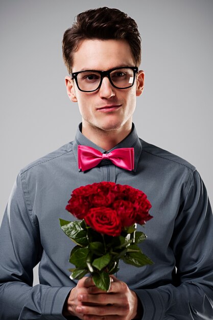 Hombre sonriente sosteniendo rosas rojas