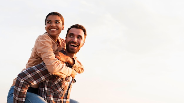 Hombre sonriente sosteniendo a su novia en la espalda con espacio de copia