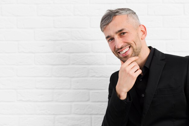 Hombre sonriente sosteniendo su rostro plano medio