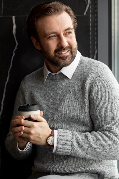 Hombre sonriente sosteniendo una taza de café de tiro medio