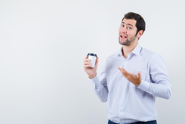 Hombre sonriente sosteniendo una taza en su mano sobre fondo blanco.