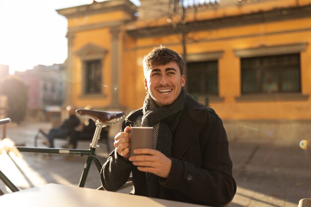 Hombre sonriente sosteniendo taza tiro medio