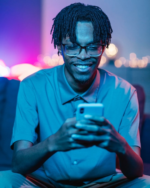 Hombre sonriente con su teléfono inteligente mientras está en casa