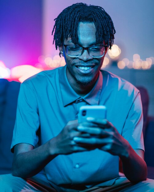 Hombre sonriente con su teléfono inteligente mientras está en casa