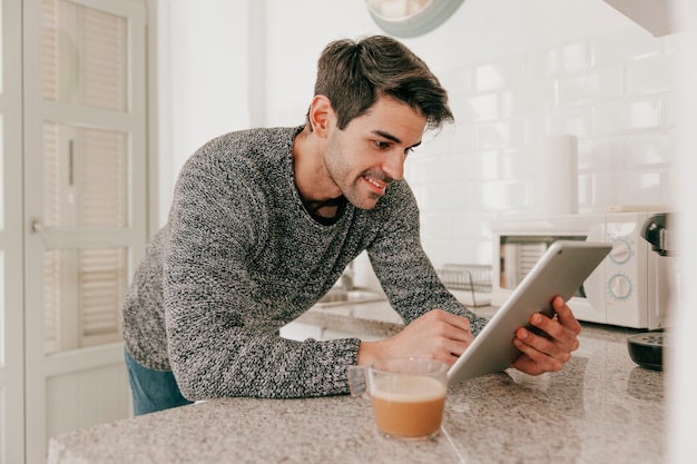 Hombre sonriente con tableta en cocina