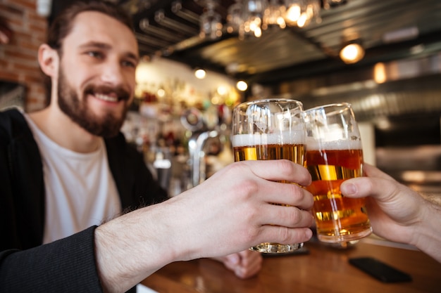 hombre sonriente tintineo gafas con amigo en el bar